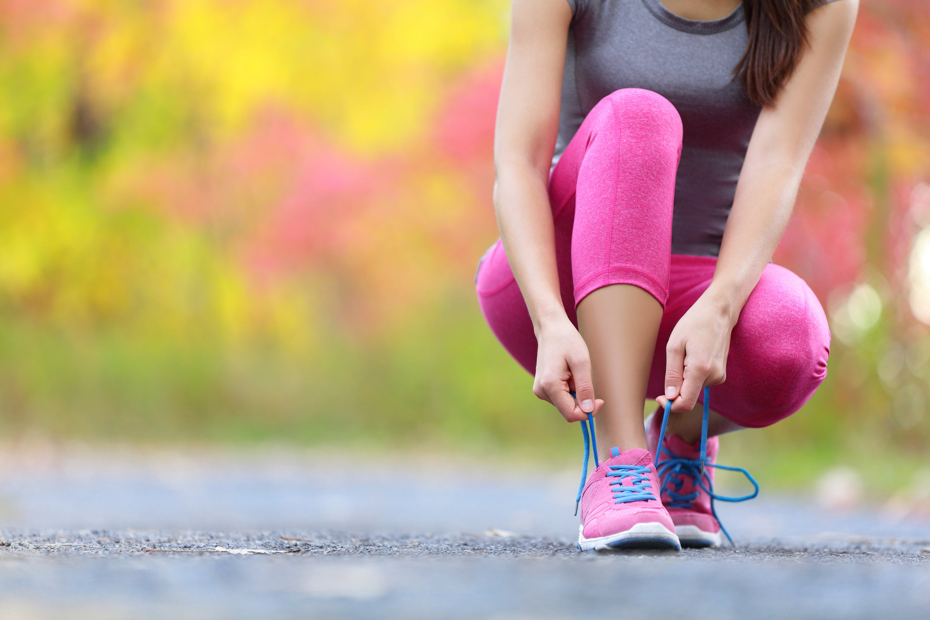 A picture of a jogger tying her shoe.